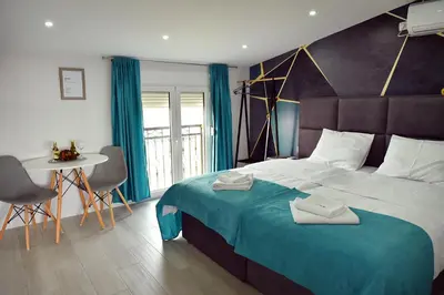 a bedroom with a large bed and a table with chairs at Studio Apartments Bulevar in Podgorica
