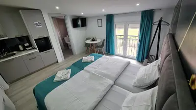 a large white bed in a room with a kitchen at Studio Apartments Bulevar in Podgorica