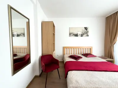 a bedroom with a bed and a mirror and a chair at Cosy two-bedroom apartment in Becici by sea and mountains in Becici