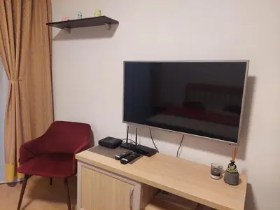 a television sitting on top of a table with a red chair at Cosy two-bedroom apartment in Becici by sea and mountains in Becici