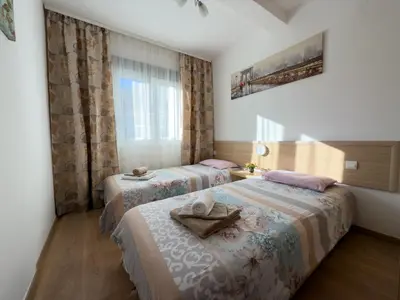a hotel room with two beds and a window at Cosy two-bedroom apartment in Becici by sea and mountains in Becici