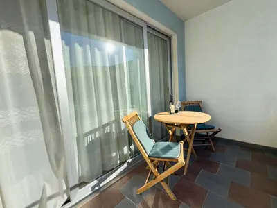 a table and chairs in a room with a large window at Cosy two-bedroom apartment in Becici by sea and mountains in Becici