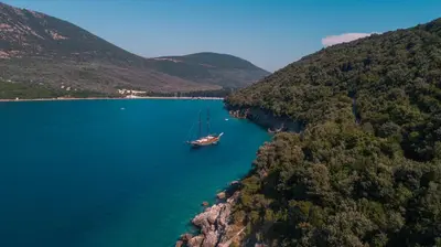 a boat in a body of water with mountains at METROPOLIS in Ulcinj
