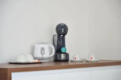 a kitchen counter with a coffee maker on a shelf at Andaluni Beach Apartments in Pržno