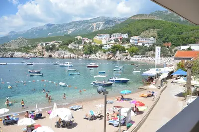 a group of people on a beach with boats in the water at Andaluni Beach Apartments in Pržno