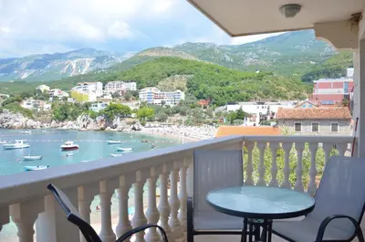 a balcony with a view of a beach and boats in the water at Andaluni Beach Apartments in Pržno