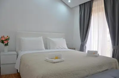 a bedroom with a white bed with two candles on it at Andaluni Beach Apartments in Pržno