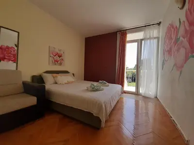 a bedroom with a bed and a window and a couch at Family apartment Garden and Sea in Petrovac na Moru