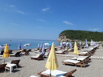 a beach with a bunch of chairs and umbrellas at Family apartment Garden and Sea in Petrovac na Moru