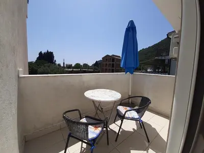 a balcony with a table and two chairs and an umbrella at Family apartment Garden and Sea in Petrovac na Moru