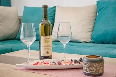 a bottle of wine and two wine glasses on a table at L’odore Del Mare in Sutomore