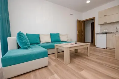 a living room with a blue couch and a table at L’odore Del Mare in Sutomore