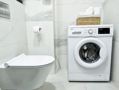 a bathroom with a washing machine and a toilet at Wonderful Apartment near City Mall in Podgorica
