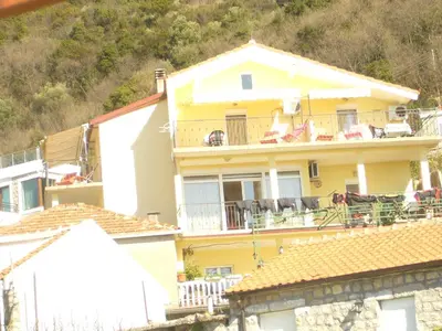 a yellow house with chairs on a balcony at MARINOVIC APARTMENTS in Budva