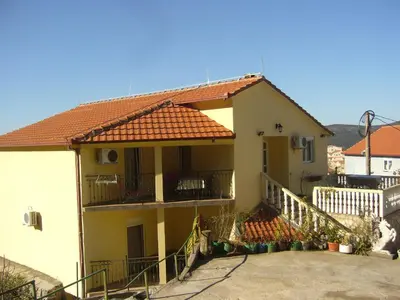 a yellow house with a staircase and a balcony at MARINOVIC APARTMENTS in Budva
