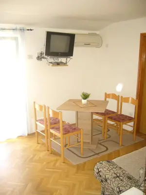 a dining room table and chairs with a television on the wall at MARINOVIC APARTMENTS in Budva