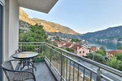 a balcony with a table and chairs and a view of the water at Java Apartments in Dobrota