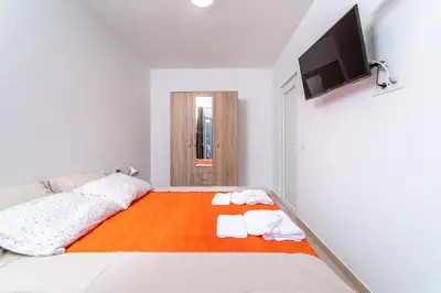 a bedroom with a bed and a flat screen tv at Java Apartments in Dobrota