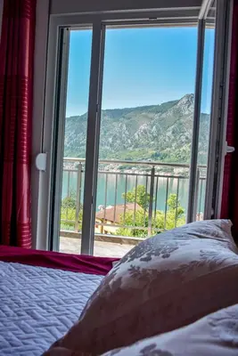 a bedroom with a large window with a view of the water at Java Apartments in Dobrota