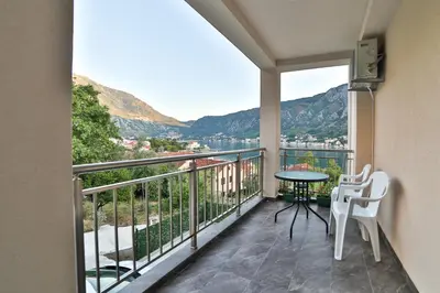 a balcony with a table and chairs and mountains at Java Apartments in Dobrota