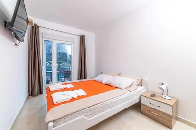 a white bedroom with a bed and a window at Java Apartments in Dobrota