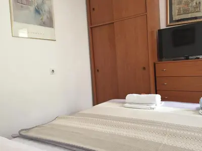 a bedroom with a bed and a dresser with a tv at Apartments Vila Andja in Sveti Stefan