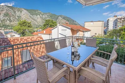 a balcony with a table and chairs and a mountain at Seafoam apartment in Kotor