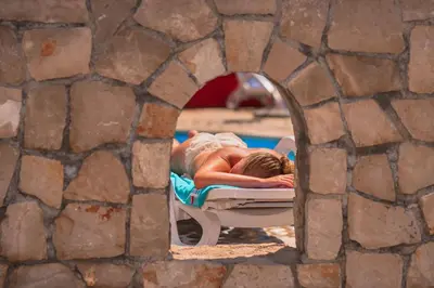 a person laying on a bed next to a pool at David Lux beach rooms in Dobra Voda