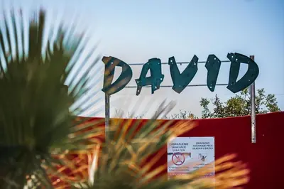 a sign for a park with a palm tree in front of it at David Lux beach rooms in Dobra Voda