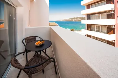 a table and chairs on a balcony with a view of the ocean at David Lux beach rooms in Dobra Voda