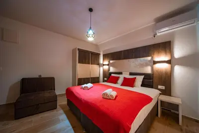 a bedroom with a red bed and a chair at David Lux beach rooms in Dobra Voda