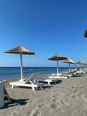 a group of lounge chairs and umbrellas on a beach at Sun and Sand Villas in Ulcinj