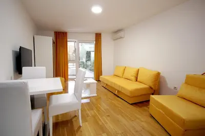 a living room with a yellow couch and a table at Holiday apartments Petrovac in Petrovac na Moru