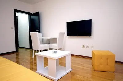 a room with a white table and chairs and a television at Holiday apartments Petrovac in Petrovac na Moru