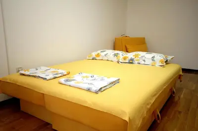 a yellow bed with two pillows on top of it at Holiday apartments Petrovac in Petrovac na Moru