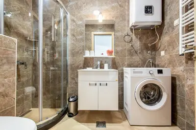 a bathroom with a washing machine and a shower at Apartment with sea view BEATRICE#26 in Rafailovici
