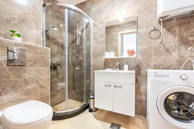 a bathroom with a shower and a washing machine at Apartment with sea view BEATRICE#26 in Rafailovici