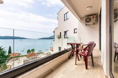 a balcony with a table and chairs and a view of the water at Apartment with sea view BEATRICE#26 in Rafailovici