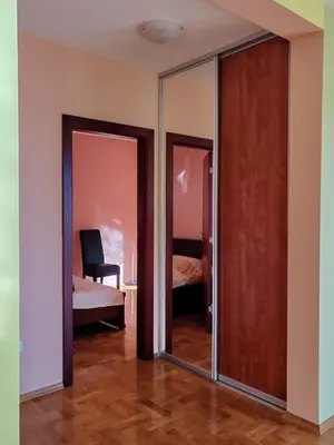 a room with mirrored doors and a bedroom with a bed at Adriatic Horizont Apartment in Petrovac na Moru