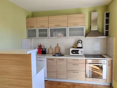 a kitchen with wooden cabinets and a microwave at Adriatic Horizont Apartment in Petrovac na Moru