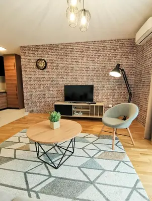 a living room with a tv and a brick wall at Apartments Overlooking the Green Hills of Ljubovic Park in Podgorica