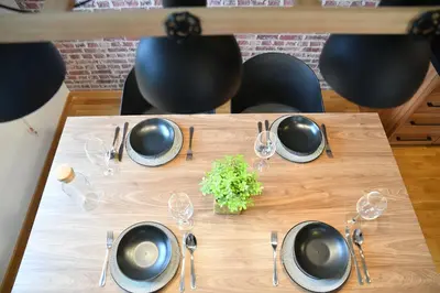 a wooden table with plates and wine glasses on it at Apartments Overlooking the Green Hills of Ljubovic Park in Podgorica