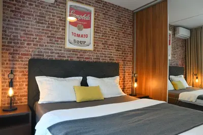 a bedroom with two beds and a brick wall at Apartments Overlooking the Green Hills of Ljubovic Park in Podgorica