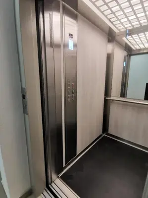 an elevator in an office building with a glass door at Apartments Overlooking the Green Hills of Ljubovic Park in Podgorica