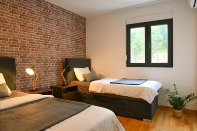 a room with two beds and a brick wall at Apartments Overlooking the Green Hills of Ljubovic Park in Podgorica