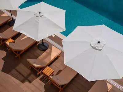an overhead view of white umbrellas and chairs next to a pool at Garden Recovery in Sveti Stefan
