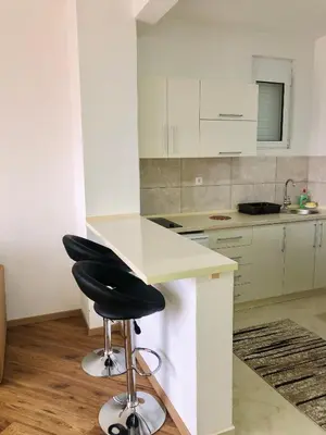 a kitchen with a white counter and a black stool at Apartments Albin in Ulcinj