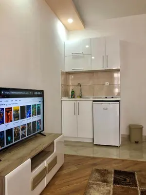 a kitchen with white cabinets and a flat screen tv at Apartments Albin in Ulcinj
