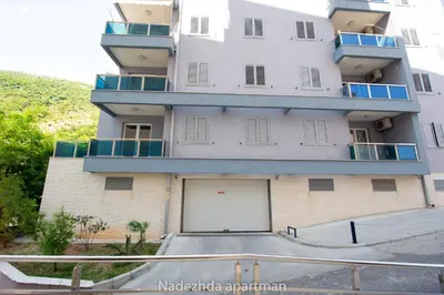 a large white building with a large garage at Marina Becici in Becici