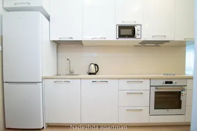 a kitchen with white cabinets and a white refrigerator at Marina Becici in Becici